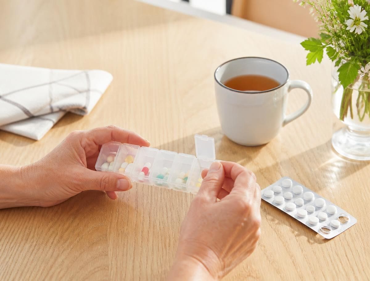 Weekly pill organiser and glass of water for medication article